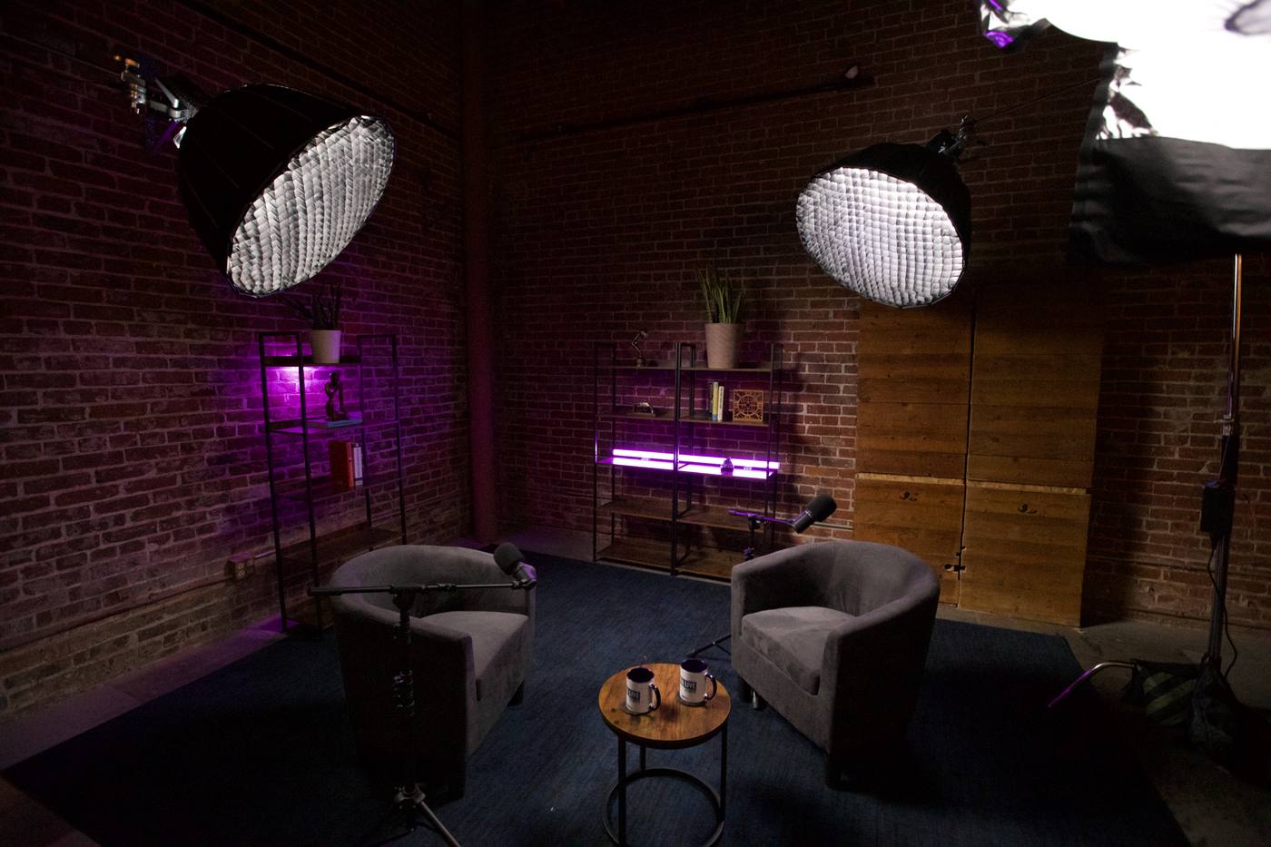 Two armchairs under softboxes with purple accent lighting on the brick set